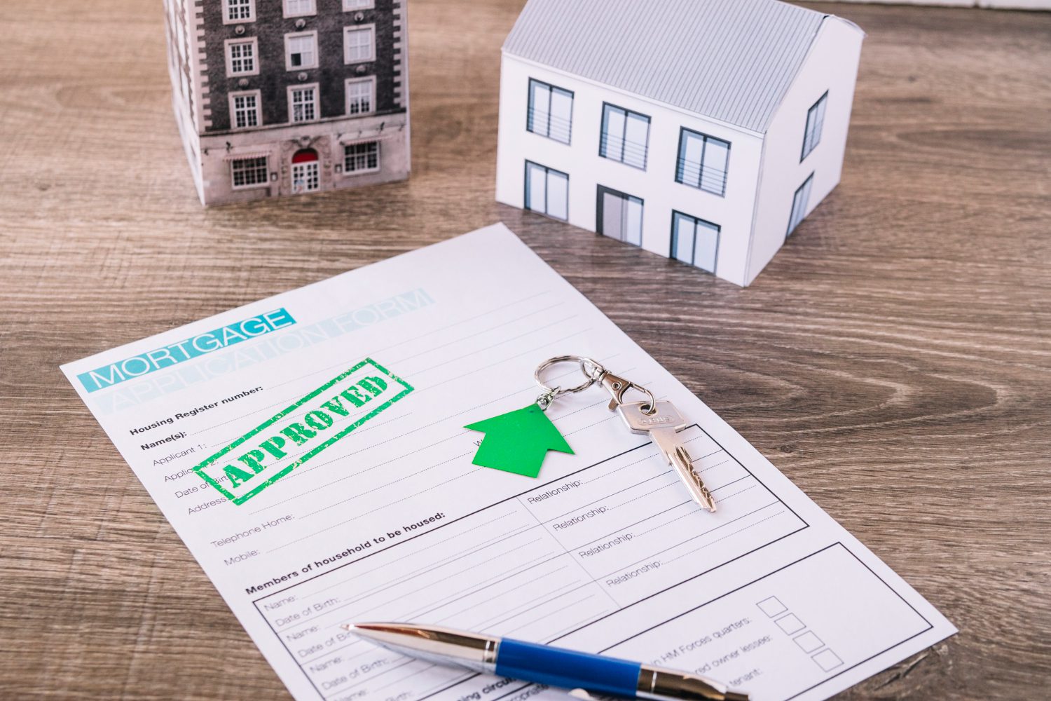 Wooden House Model With Keys And Mortgage Documents On A Table During A Real Estate Transaction